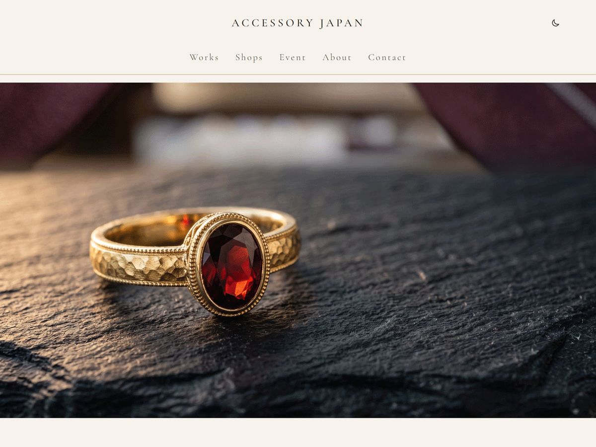 The Genva Craft front page. The site name in the centre, with Works, Shops, Event, About and Contact below it. A wide photograph of a gold ring with a garnet on a dark slate fills the page